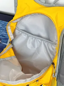 Vue interieure detaillee du sac a dos montrant la poche zippee et la doublure grise.