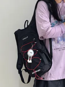 Détail de sac à dos de randonnée léger avec cordons rouges et pendentif poupée en peluche.