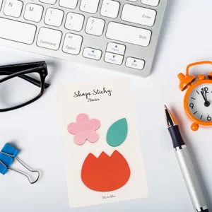 Detailed close-up of colorful shape sticky notes on white desk with keyboard, pen and clock.