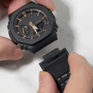 Close-up detail of black watch case with rose gold accents and strap connector adapter.