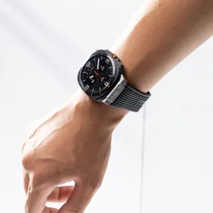Close-up detail of black silicone watch strap featuring metal buckle worn on wrist.
