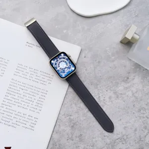 Dettaglio cinturino orologio in pelle scura, trama litchi con connettore in metallo.