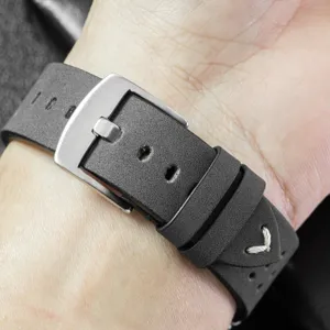 Detailed view of black leather watch strap with silver metal buckle and breathable holes.