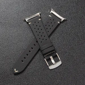 Close-up of black perforated leather watch strap with white stitching and metal buckle details.