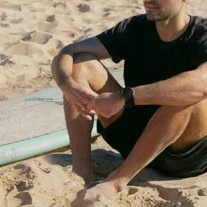 Close-up van een zwarte nylon klittenband horlogeband gedragen om de pols op het strand.