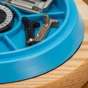 Parti di riparazione di orologi e componenti di movimento in un vassoio blu su legno.