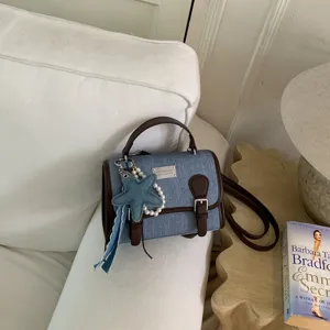 Borsa a mano mini in denim chic con bordo in pelle marrone e ciondolo con perle.