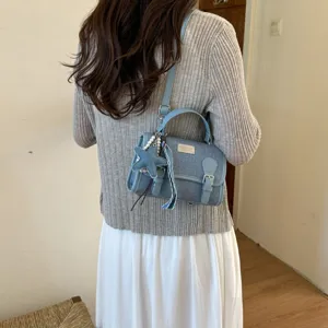 Dettaglio della borsa in jeans blu con placca in metallo, fibbia e grazioso ciondolo a stella.