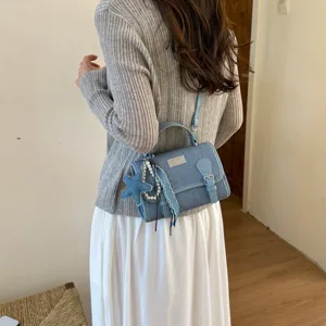 Vista dettagliata della borsa in denim azzurro elegante con ciondoli di perle e stelle.