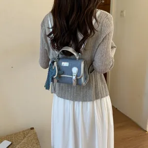 Elegante piccolo zaino in jeans da donna, design di tendenza in pelle argentata con ciondolo.