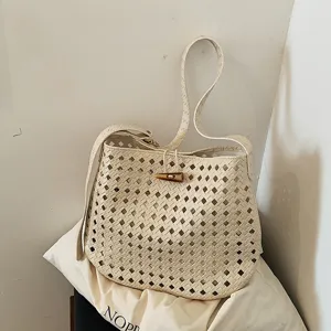 Vista ravvicinata dell'elegante borsa a secchiello beige con dettagli di trama intrecciata.