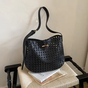 Vista dettagliata di una borsa a tracolla nera intrecciata con motivo traforato e chiusura chic.