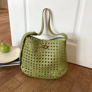 Dettaglio della borsa a spalla in pelle intrecciata verde con trama elegante e chiusura a levetta.