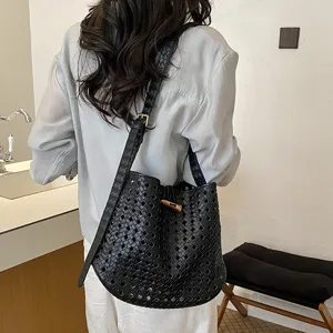 Vista dettagliata di una borsa a secchiello in pelle intrecciata nera con chiusura a leva.