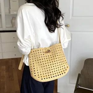 Primo piano dettagliato della elegante borsa a tracolla intrecciata con trama traforata.