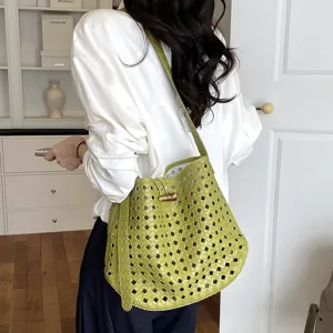 Vista di dettaglio della elegante borsa a spalla verde intrecciata con design traforato.
