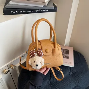 Primo piano della borsa a mano gialla elegante con ciondolo in peluche di cucciolo.