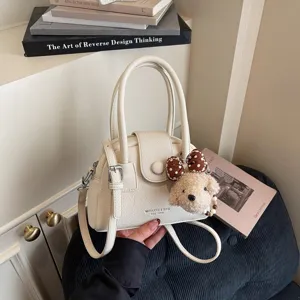 Elegante borsa beige a conchiglia con ciondolo di cucciolo in peluche, perfetta per pendolari.