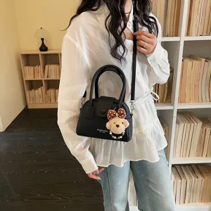 Elegante borsa a tracolla a conchiglia nera da donna con grazioso ciondolo a orsetto.