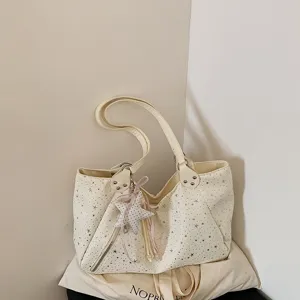 Detail shot of cream white shoulder tote bag with star pattern and cute plush star pendant.