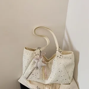 Detailed view of cream star print shoulder tote bag with cute star charm and zipper pocket.