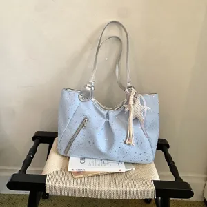 Detailed view of light blue star print shoulder tote bag with silver straps and star charm.