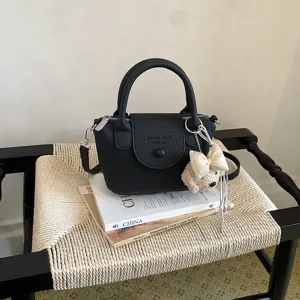 Vista dettagliata di una chic borsa a secchiello nera in pelle con manico e ciondolo.