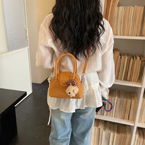Vista dettagliata dell'elegante borsa a tracolla gialla con un simpatico ciondolo di peluche.