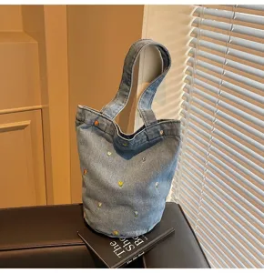 Détail de sac seau en denim chic avec jolie broderie florale et style décontracté tendance.