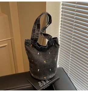 Vue détaillée du sac seau en denim gris foncé avec de délicats motifs floraux brodés.