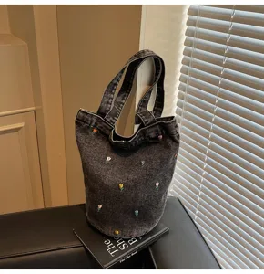 Détail de sac seau en denim avec tulipes brodées mignonnes et texture lavée vintage.