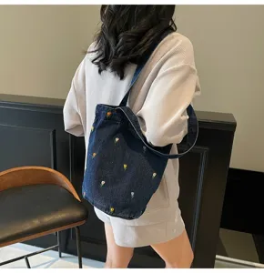 Vue détaillée d'un sac seau élégant en jean avec de jolies broderies de fleurs.