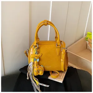Chic yellow shoulder crossbody bag with cute giraffe charm and elegant lace fringe for women.