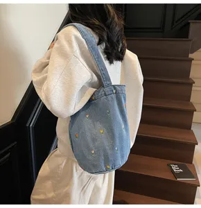 Détail de sac seau en denim chic avec délicate broderie de tulipes colorées pour trajets.