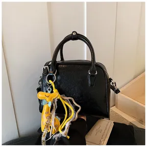 Black leather shoulder handbag with cute yellow giraffe charm, versatile commuter daily bag.