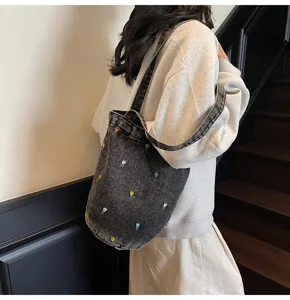 Vue détaillée du sac seau en denim gris foncé avec des motifs de tulipes brodées colorées.