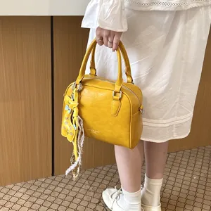 Detail shot of yellow PU leather shoulder bag featuring a cute giraffe charm and lace ribbon.