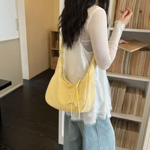 Vista di dettaglio di una borsa a tracolla giallo chiaro con stampa di stelle e ciondolo chic.
