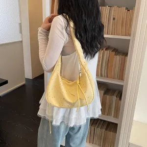Vista di dettaglio di una borsa a tracolla gialla con stampa di stelle e ciondolo.