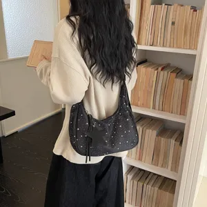 Vista dettagliata della borsa a spalla nera con stampa a stelle e ciondolo carino.