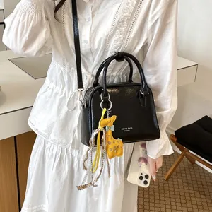 Black shoulder crossbody bag with cute yellow giraffe charm, chic commuter handbag for women.