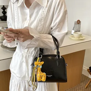 Detail view of black leather crossbody bag featuring cute yellow giraffe keychain.