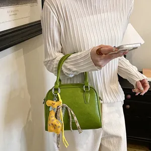 Fashionable green shoulder handbag with cute giraffe charm, perfect for daily commute.