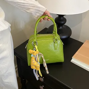 Green leather shoulder crossbody boston bag detail view with cute yellow giraffe charm.