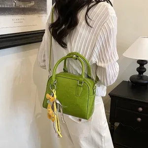 Detail view of the green shoulder bag with cute giraffe charm and textured leather finish.