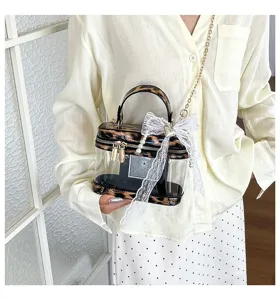Bolso vanity transparente con un delicado lazo de encaje blanco y ribete de leopardo.