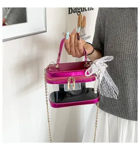 Detalle del bolso de mano tipo caja rosa transparente con lazo de encaje y cadena.