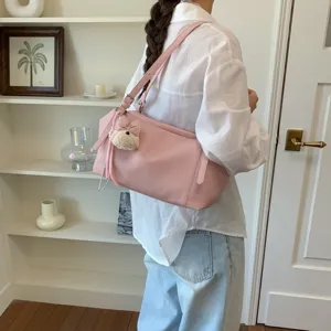 Vista detallada del bolso de hombro rosa de cuero suave con textura y un hermoso colgante.