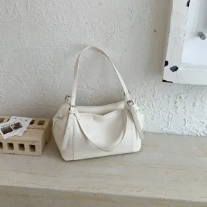 Vista detallada del bolso de hombro de cuero suave blanco con diseño de hebillas.