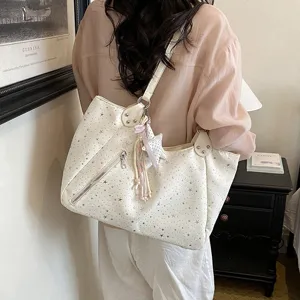 Detailed view of a trendy white star print shoulder tote bag with zipper pocket and charm.